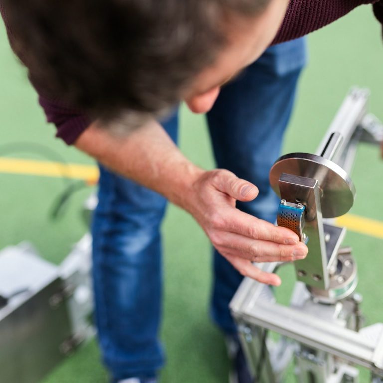 Eine Person justiert ein mechanisches Gerät auf einer grünen Fläche.