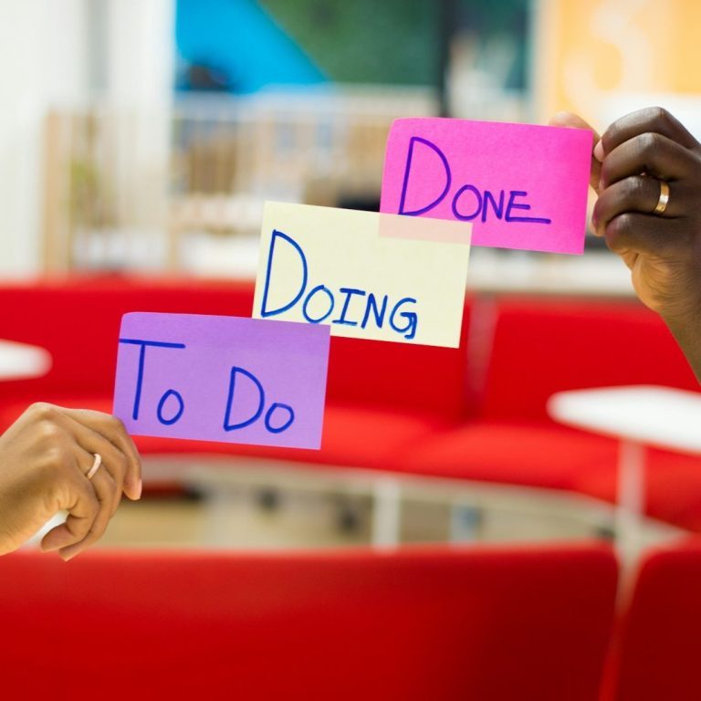 Hände halten bunte Karten mit den Wörtern "To Do", "Doing" und "Done".