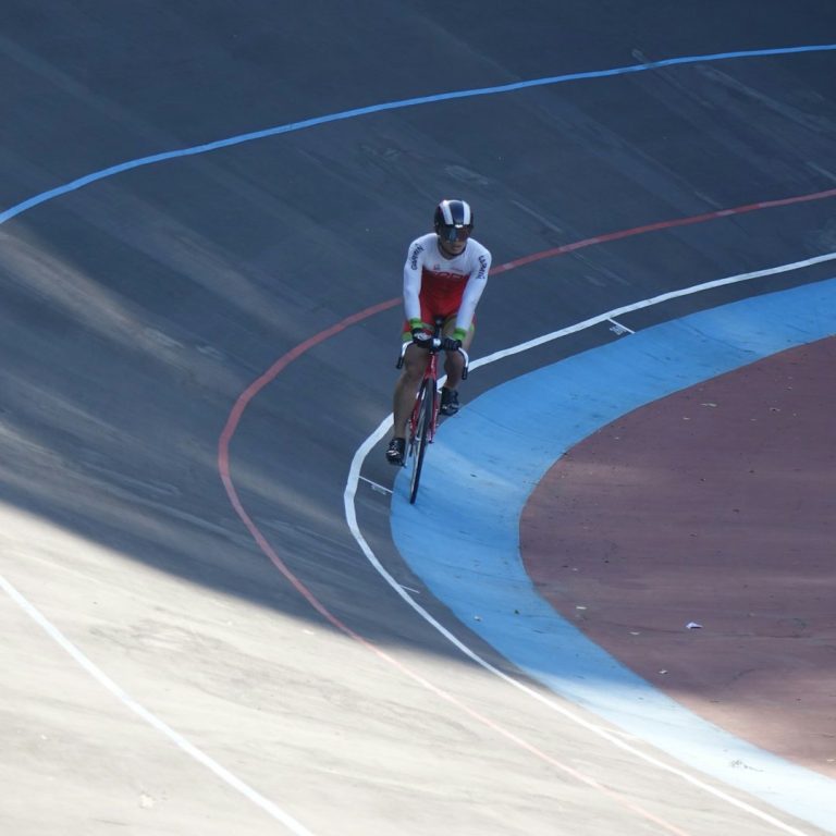Radfahrer auf einer Rennbahn, der in einer Kurve fährt.